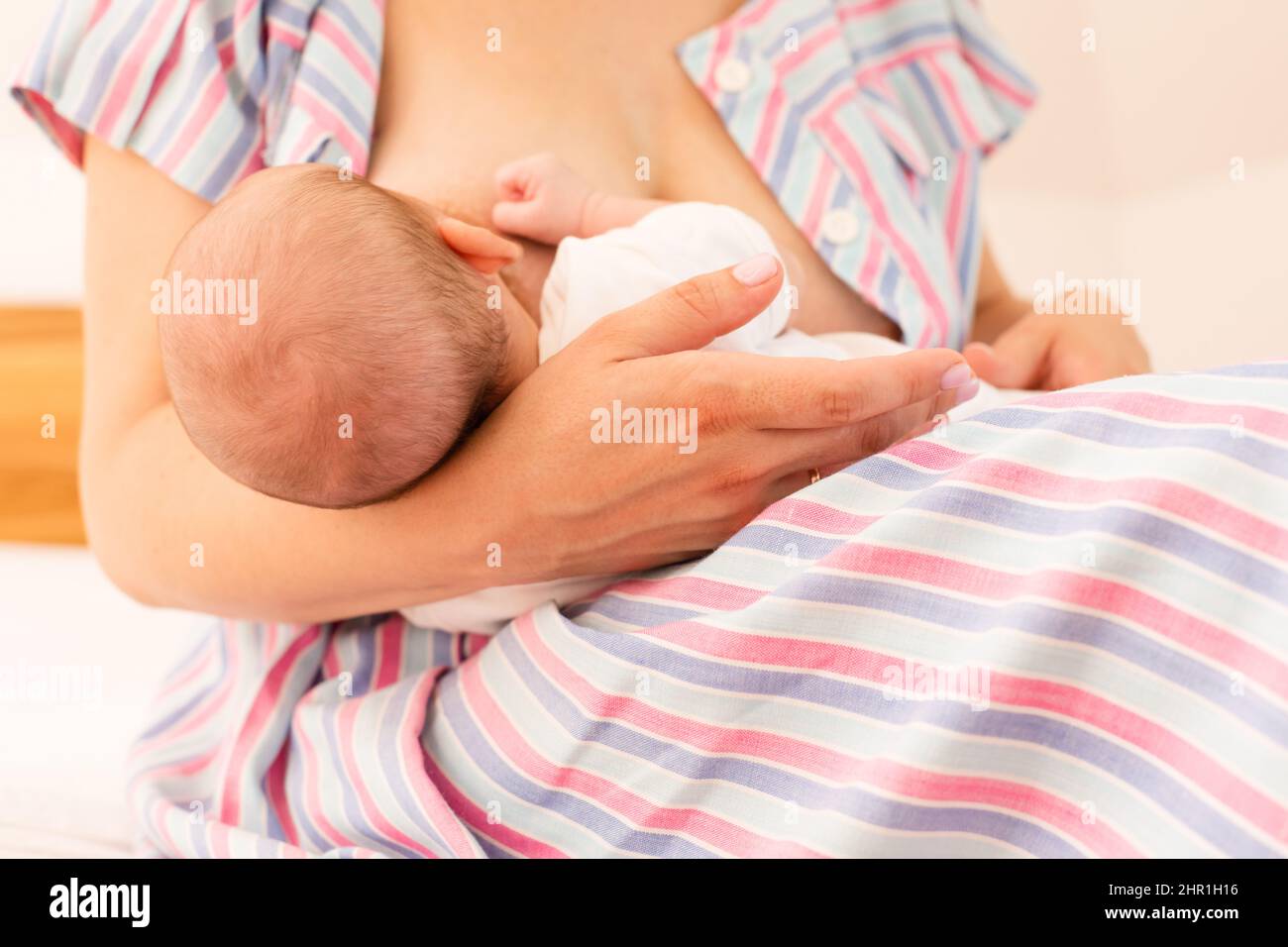 Die Mutter stillt ihr neugeborenes Baby auf dem Bett Stockfoto