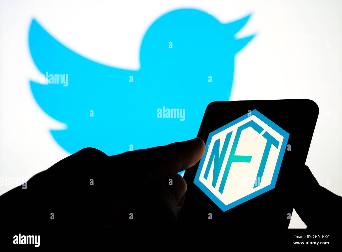 NFT-Logo auf dem Bildschirm des Smartphones und verschwommenes Twitter-Logo auf dem Hintergrund. Selektiver Fokus. Stafford, Großbritannien, 24. Februar 2022 Stockfoto