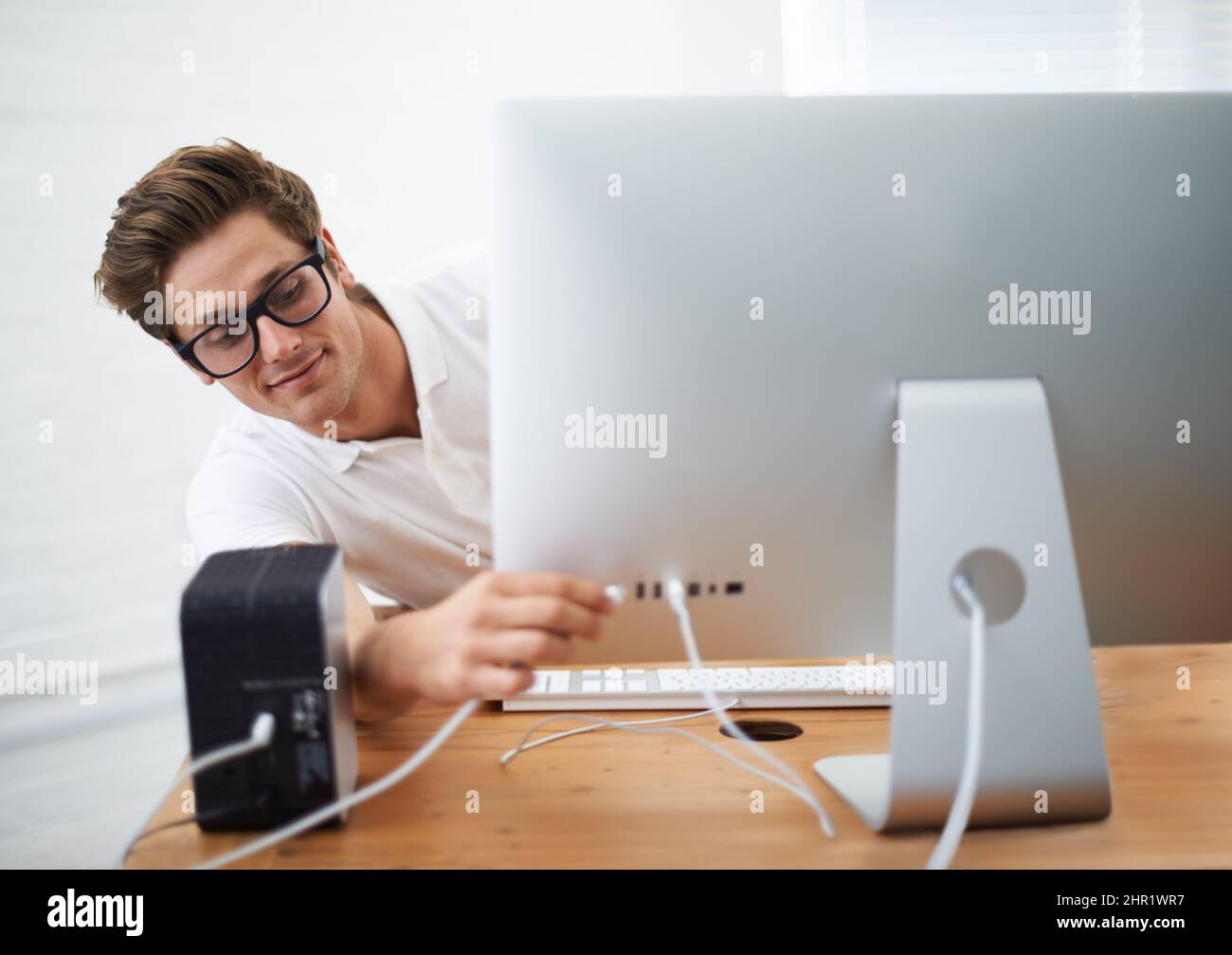 Ich habe das verstanden. Ein junger Mann, der ein Kabel an seinen Computer anschließt. Stockfoto