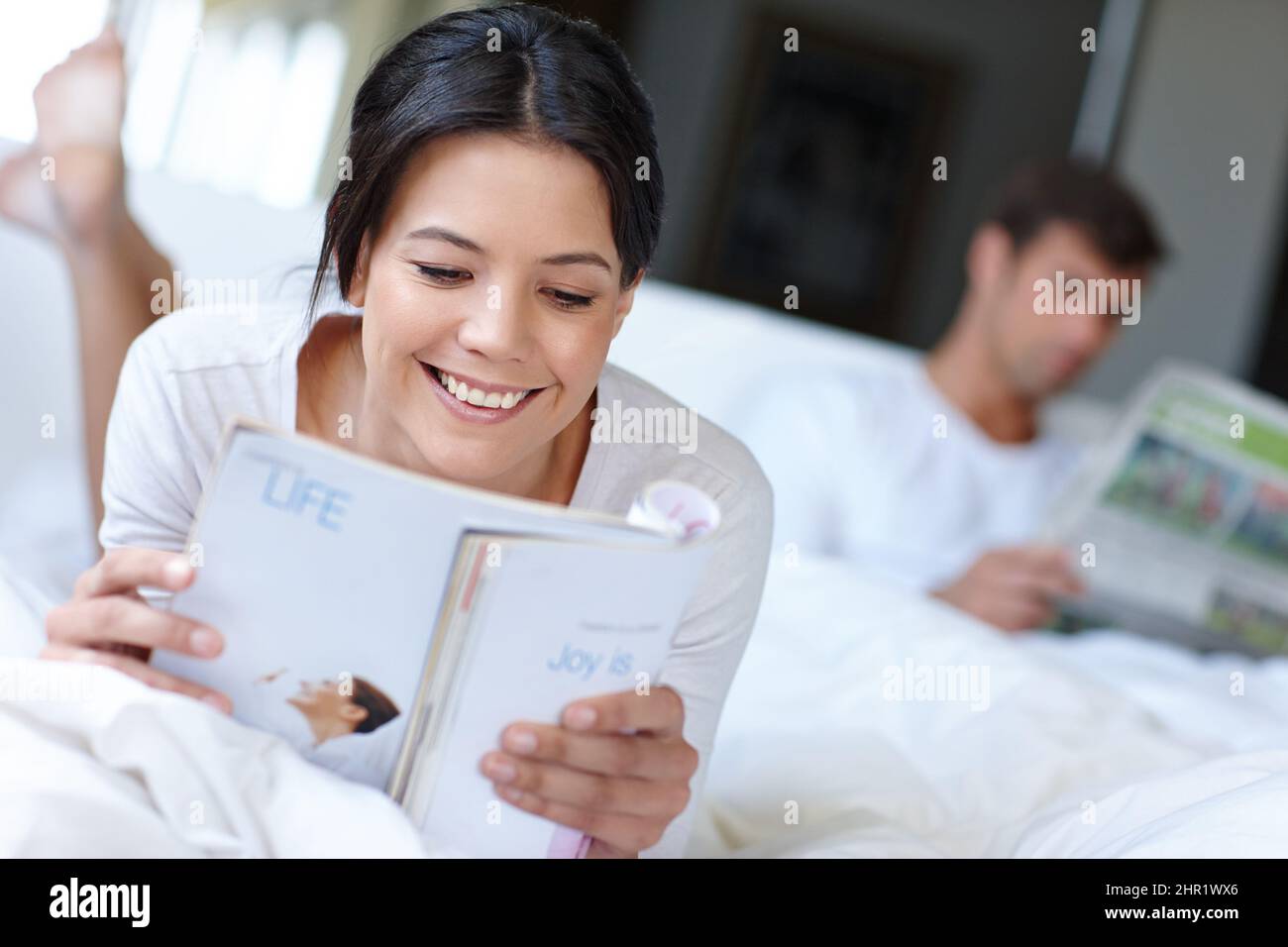 Je mehr Sie lesen, desto mehr wissen Sie. Aufnahme einer schönen Frau, die im Bett liegt und eine Zeitschrift liest. Stockfoto