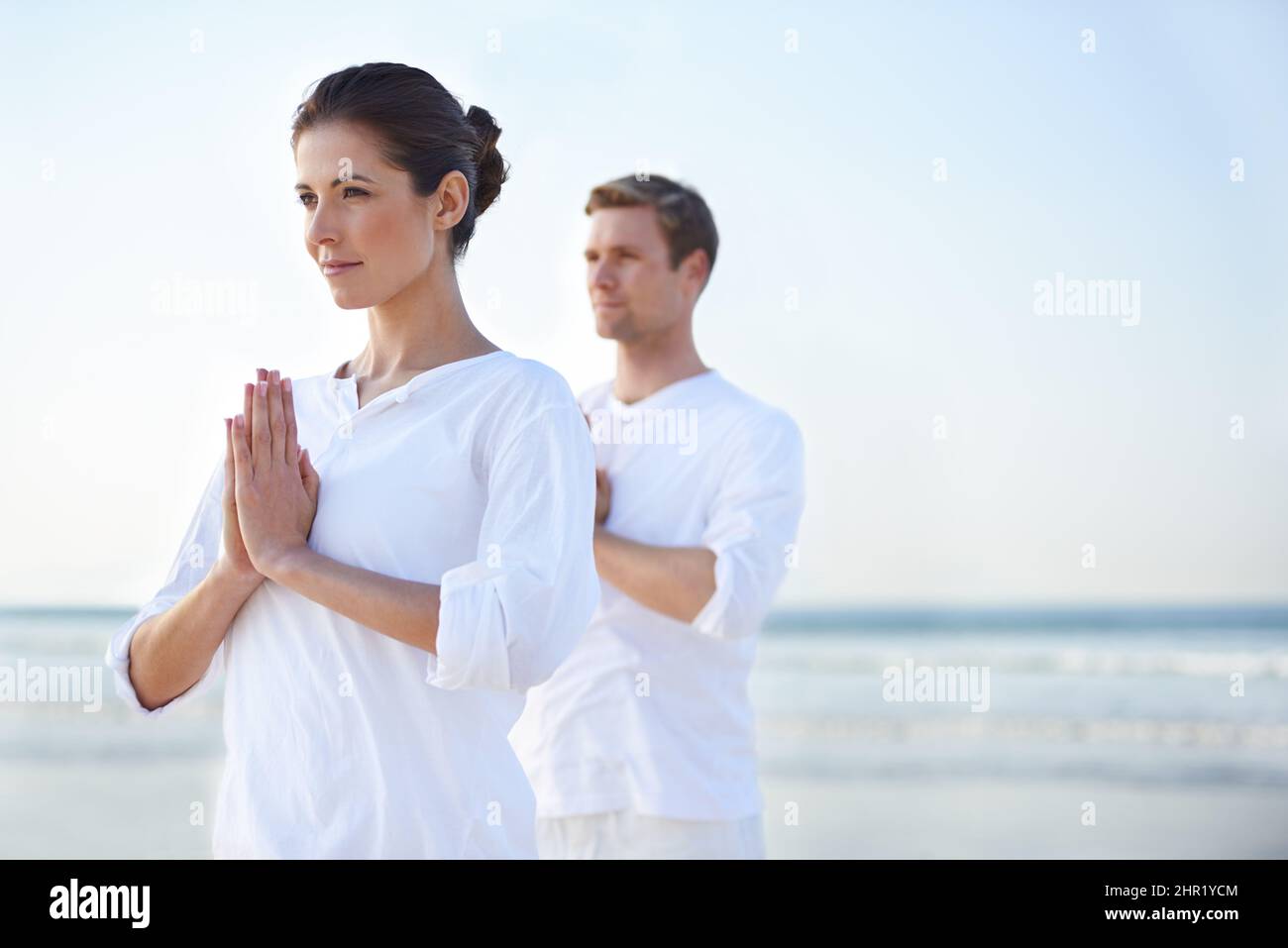 Yoga am Meer. Ein junges Paar, das am Strand Yoga praktiziert. Stockfoto