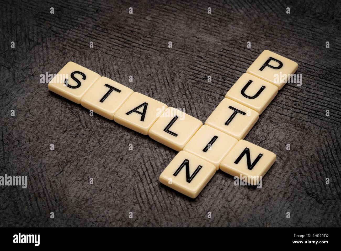 Kreuzworträtsel von Putin und Stalin in elfenbeinfarbenen Buchstabenkacheln gegen strukturiertes handgefertigtes Papier Stockfoto