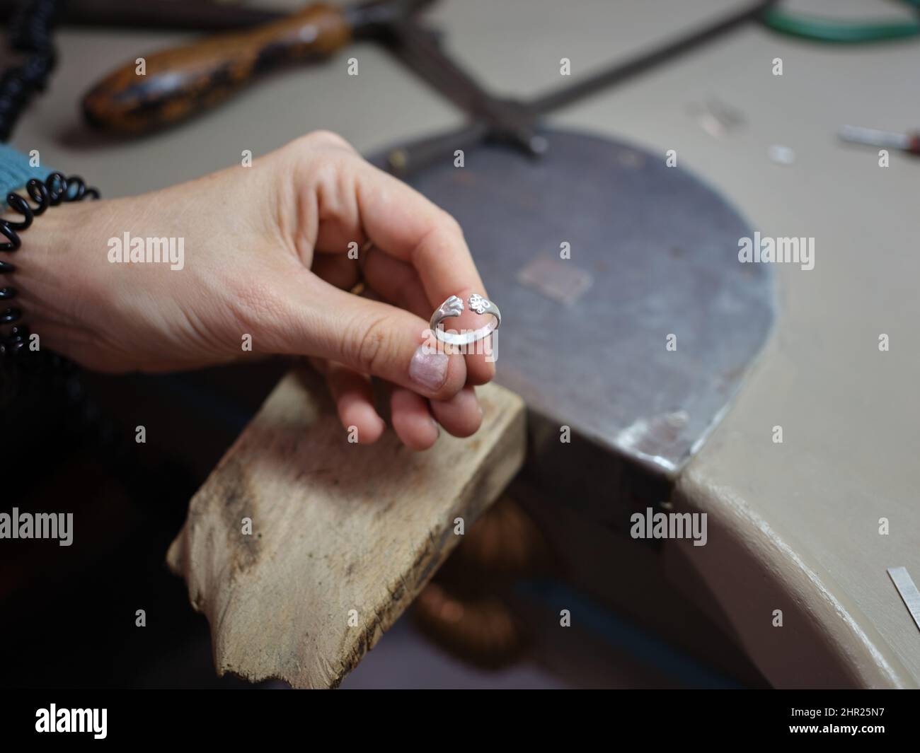 Eine Erwachsene Frau mit einem Ring, den sie in ihrer Schmuckwerkstatt zu machen beginnt Stockfoto