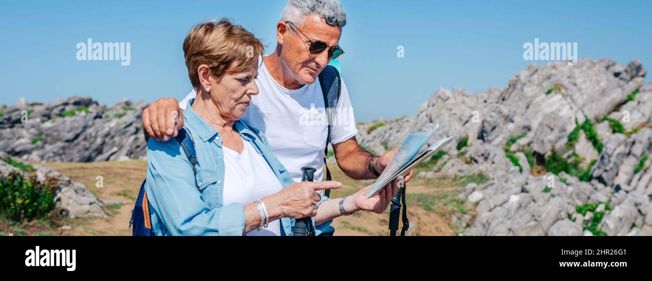 Seniorenpaar mit Stöcken auf Wanderkarte Stockfoto