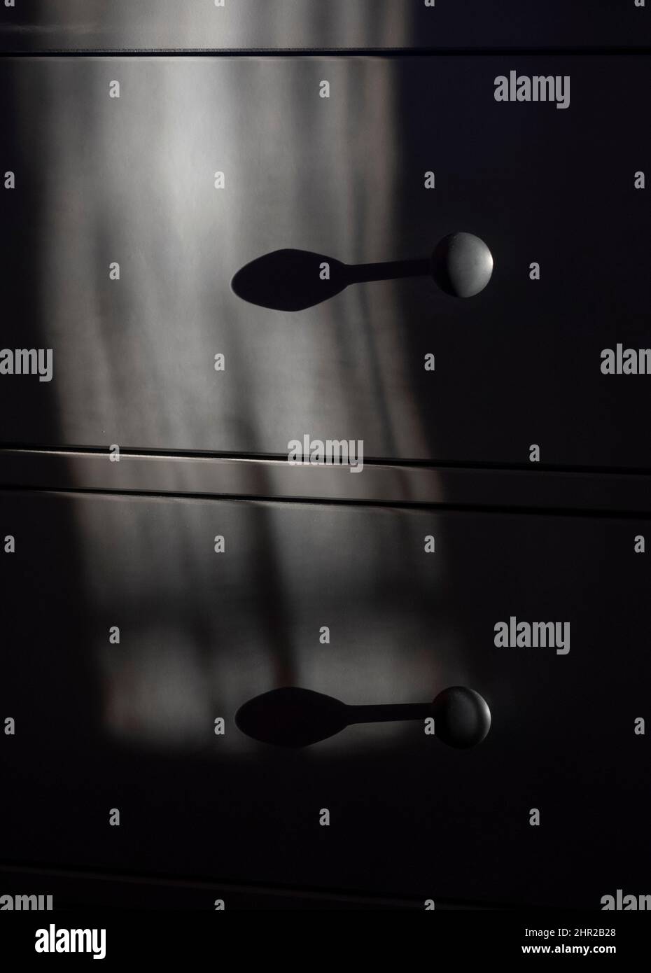 Das erste Licht des Tages, das durch Vorhänge scheint, wirft Schatten auf eine Reihe von Schlafzimmerstichen Stockfoto