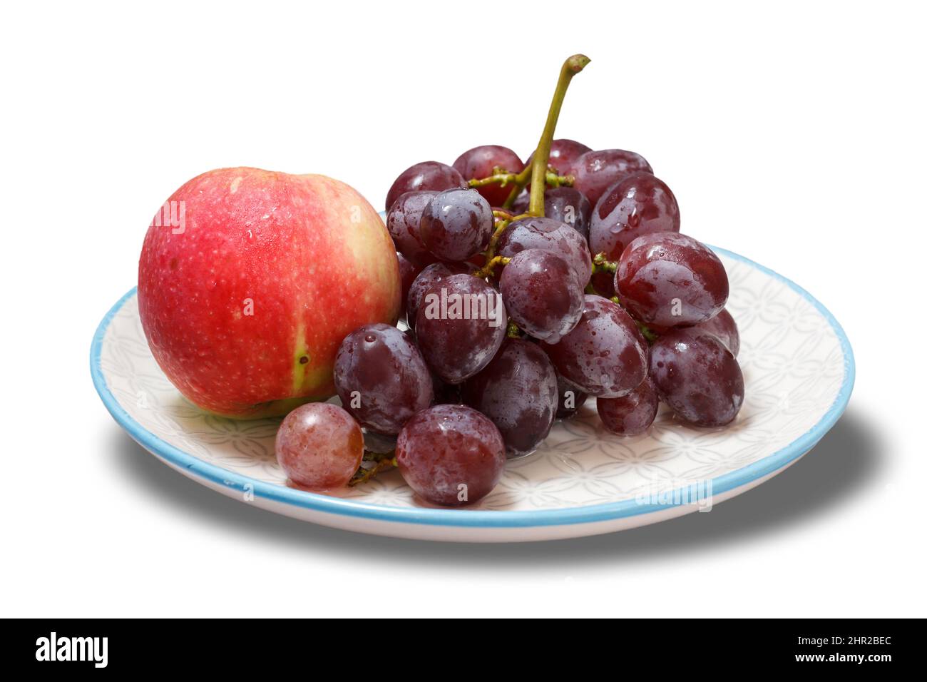 Bund grüner Trauben und Apfel auf weißem Teller. Stockfoto