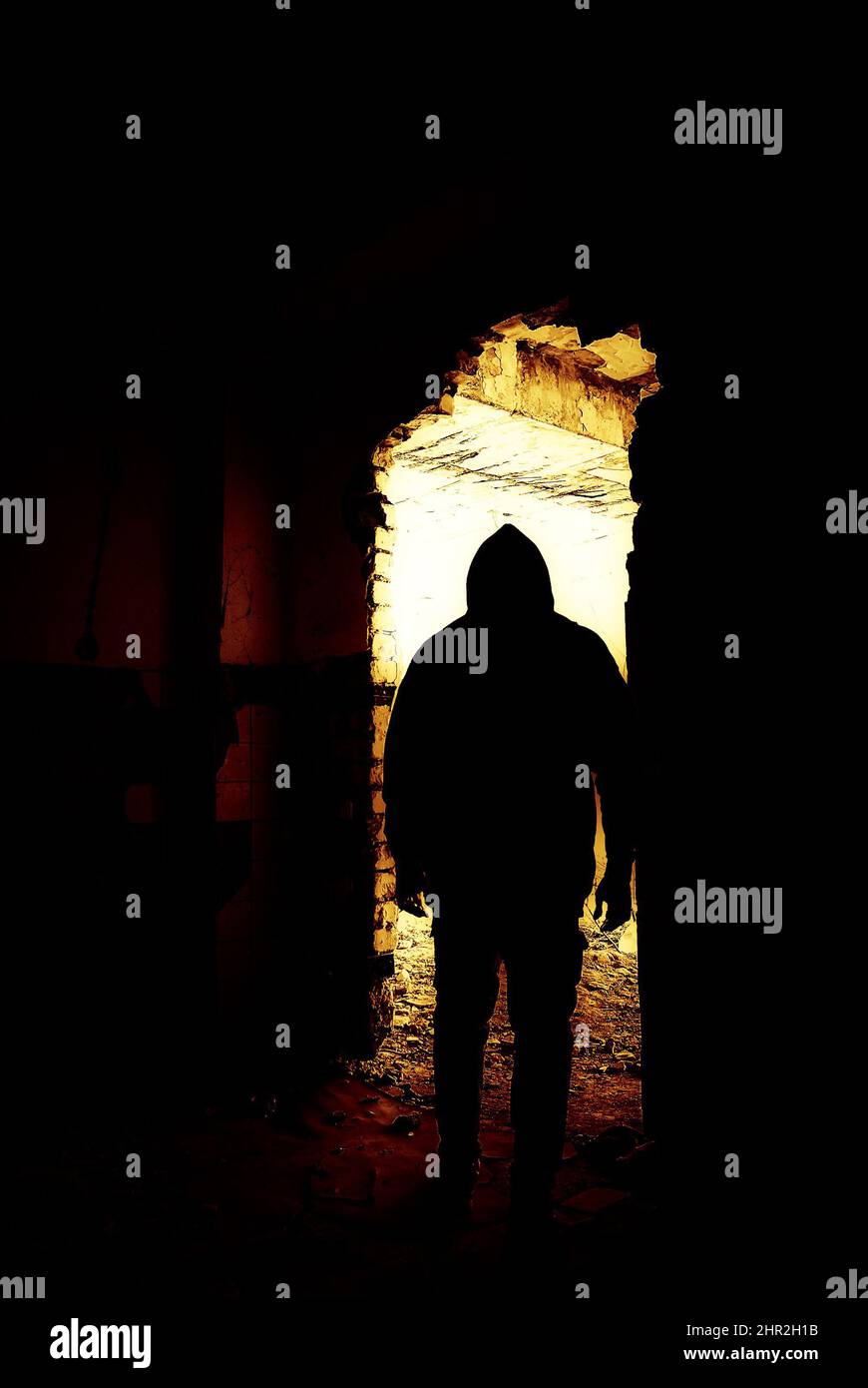 Schwarze menschliche Silhouette in einer Tür. Menschliche Silhouette an einem verlassenen und ruinierten Ort, der zu hellem Licht wird. Stockfoto