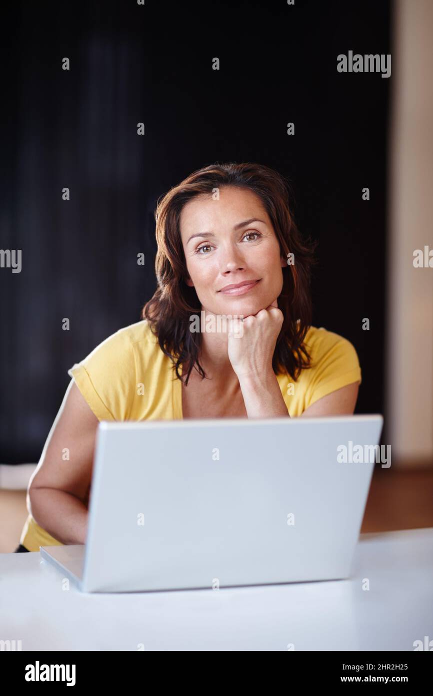 Denken Sie etwas, um ihren Kalender hinzuzufügen. Eine junge Frau, die zu Hause an ihrem Laptop arbeitet. Stockfoto
