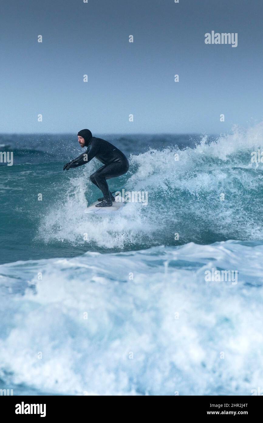 Ein Surfer, der im Fistral in Newquay in Cornwall in Großbritannien spektakuläre Winter-Surfing-Action genießt. Stockfoto