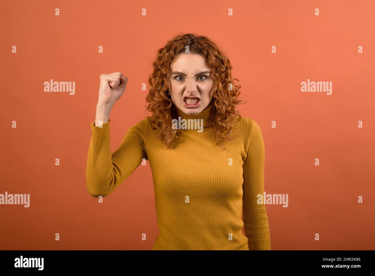 Junge und attraktive Rotschopf kaukasischen Mädchen schreiend, sie ist wütend und wütend isoliert auf orangen Studio-Hintergrund. Stockfoto