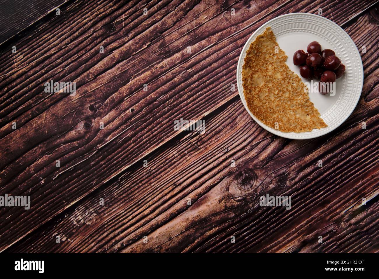 Von oben aufgenommen, flaches Bild eines halben Pfannkuchens mit schwarzen Kirschen aus der Dose. Stockfoto