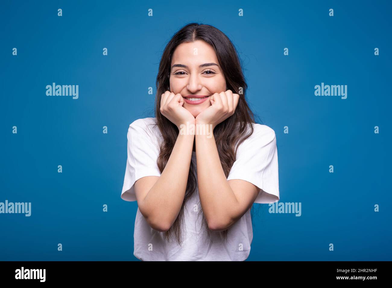 Portrait von glücklichen und attraktiven kaukasischen oder arabischen Brünette Mädchen in weißem T-Shirt isoliert auf blauem Studio-Hintergrund. Stockfoto