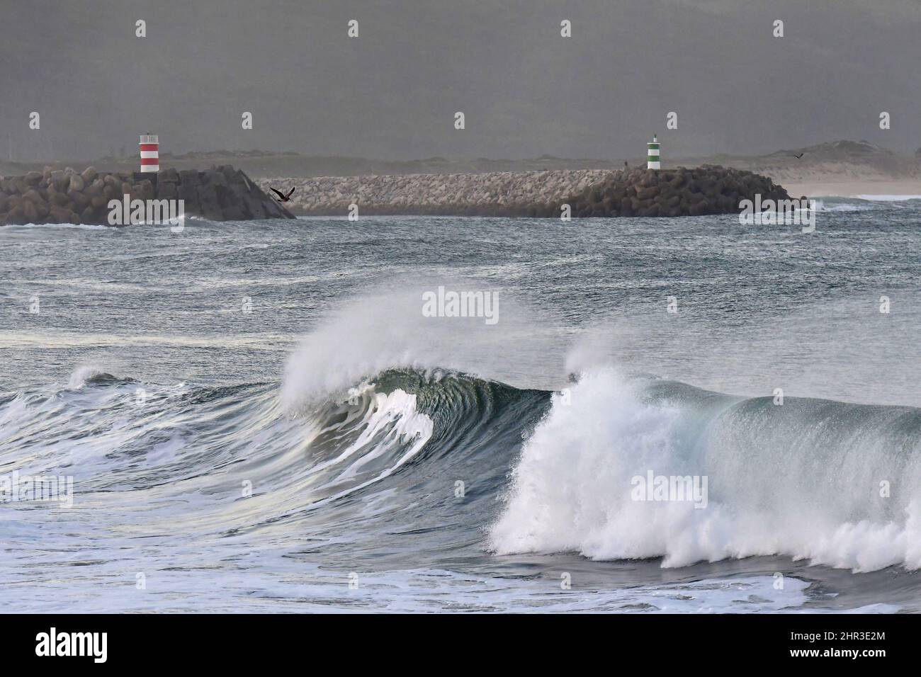 Steinpier mit Leuchttürmen, große Wellen krachen an der Küste von Nazare in Portugal. Stockfoto