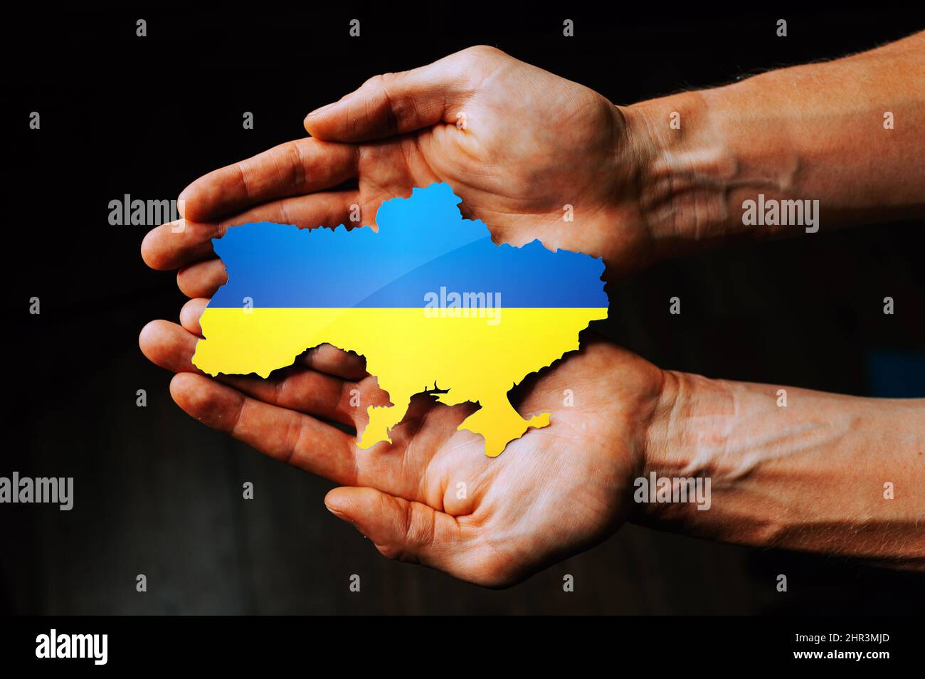 Unterstützung der Ukraine im Krieg mit Russland. Hände, die die Flagge der Ukraine in Form der Grenzen der Ukraine halten. Stockfoto