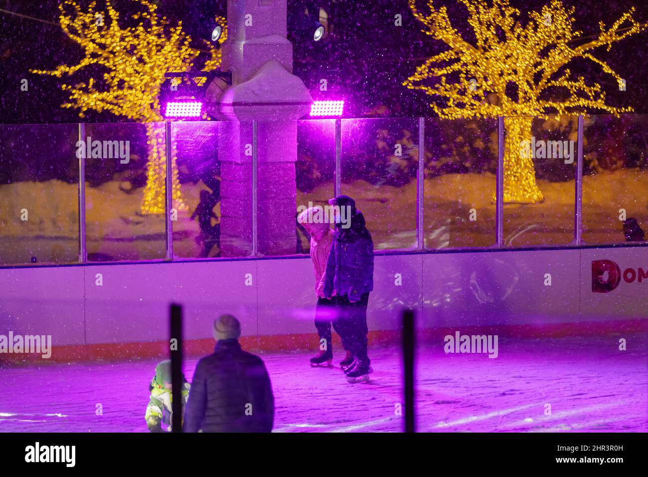 Abends Schlittschuh auf einer beleuchteten Eisbahn. Ein Schneesturm wütet und Schnee fällt. Selenograd, Russland 28.01.2022. Stockfoto
