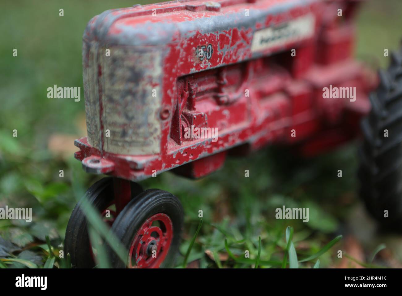 Selektive Fokusaufnahme eines roten Traktorspielzeugs im Gras Stockfoto