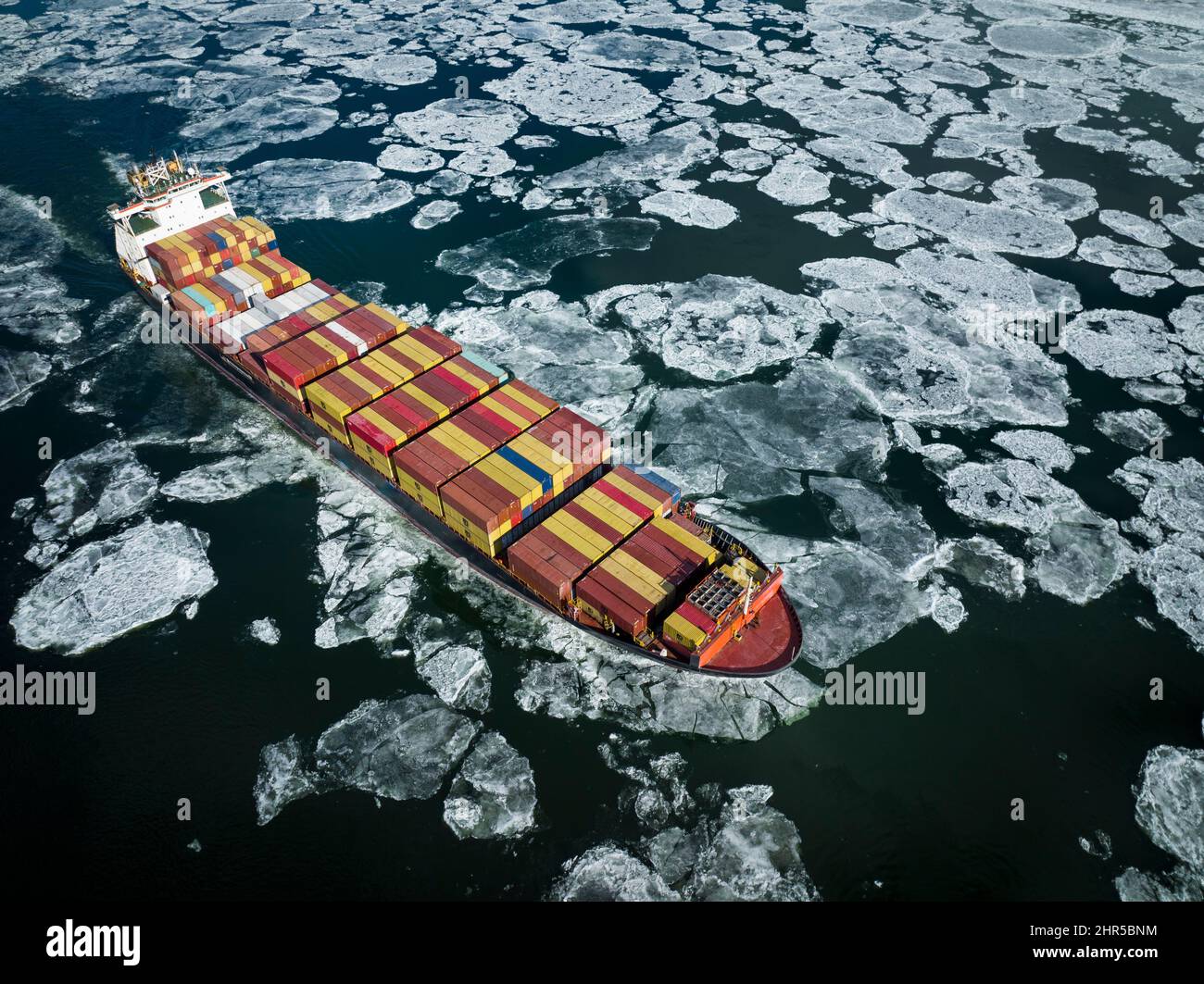 Luftaufnahme eines Containerschiffes, das stromaufwärts durch Wintereis im St. Lawrence River in der Nähe des Hafens von Montreal in Kanada fährt Stockfoto