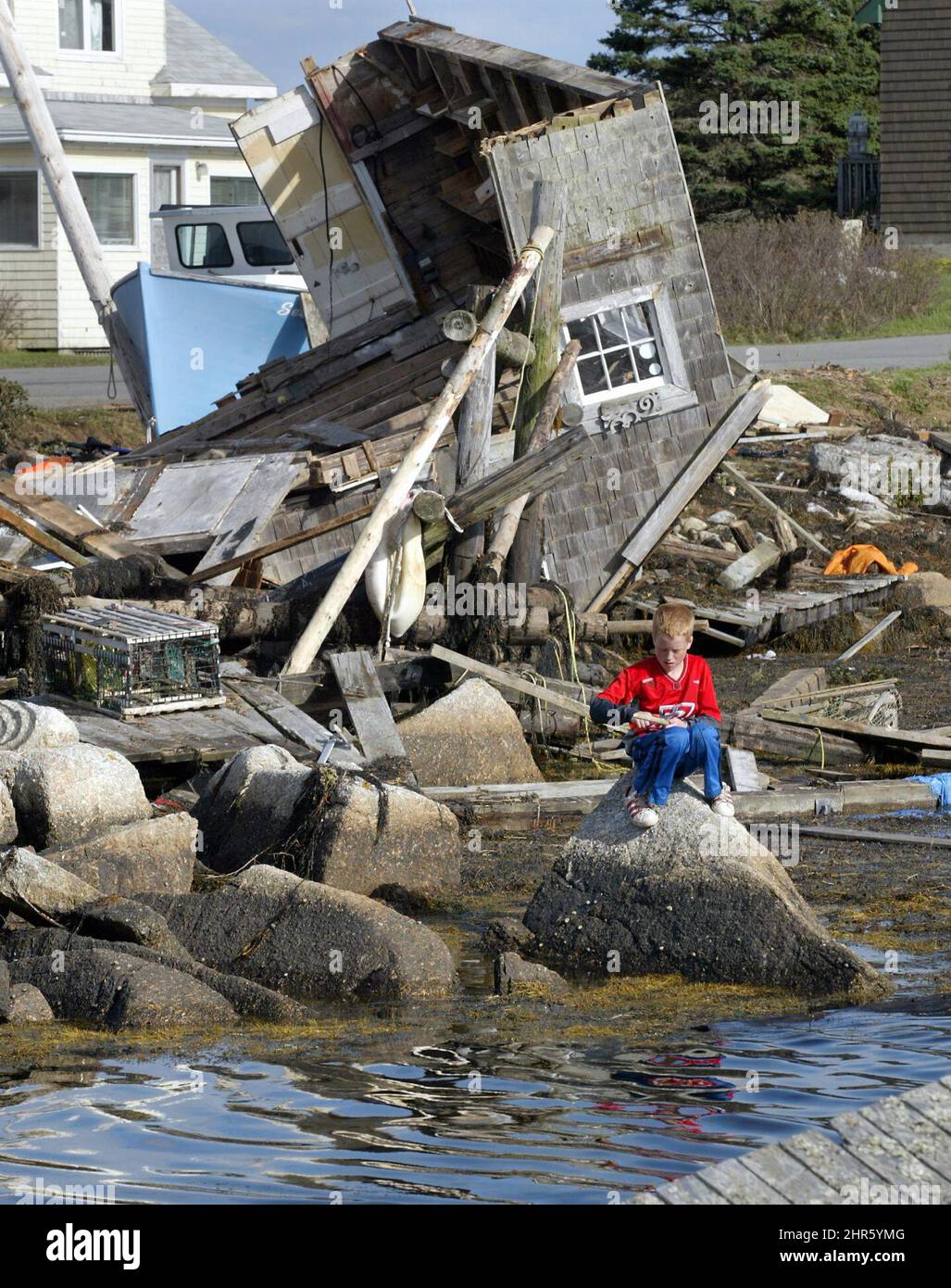 Jason Benn, 12, schnitzt in Prospect, N.S. ein Stück Holz Ein Fischerboot von Joe Duggan ruht am Ufer, das während des Hurrikans Juan von den Wellen und dem Wind geschleudert wurde. Die Fischer an der Küste von Nova scotia stehen nach dem Sturm, der das Gebiet verwüstet hat, vor einer ungewissen Zukunft. (CP-FOTO/Andrew Vaughan) Stockfoto