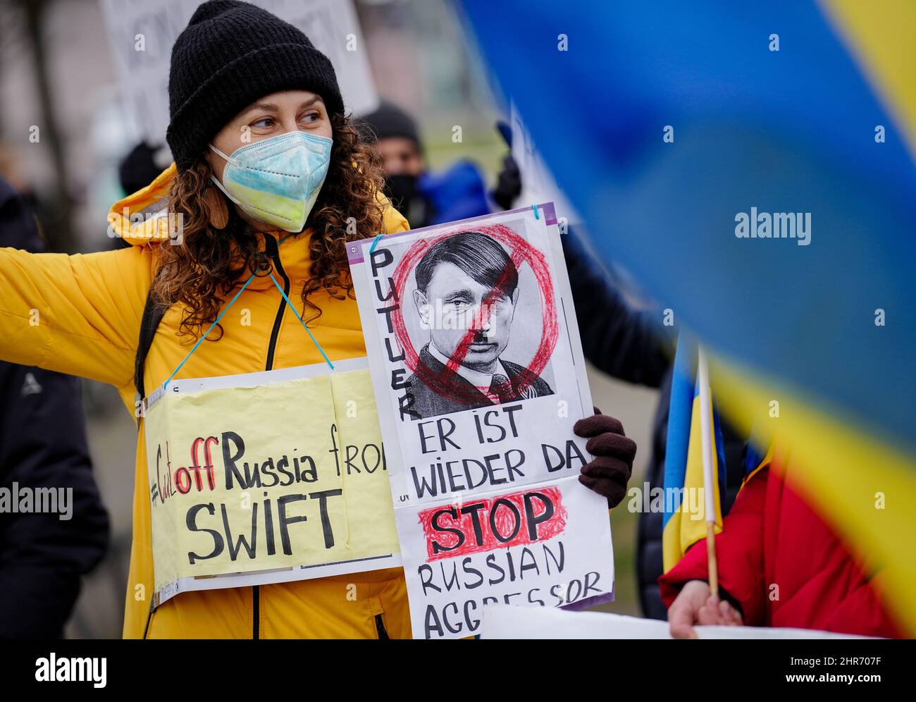 Berlin, Deutschland. 25.. Februar 2022. Teilnehmer einer Demonstration protestieren vor dem Bundeskanzleramt gegen den Krieg und die russische Invasion in der Ukraine. Eine junge Frau hält ein Schild mit einem Bild eines Gesichts, das eine Mischung aus Hitler und Putin ist. Daneben steht die Schrift 'Putler' - ein Neologismus, der aus den Namen 'Putin' und 'Hitler' besteht. Quelle: Kay Nietfeld/dpa/Alamy Live News Stockfoto