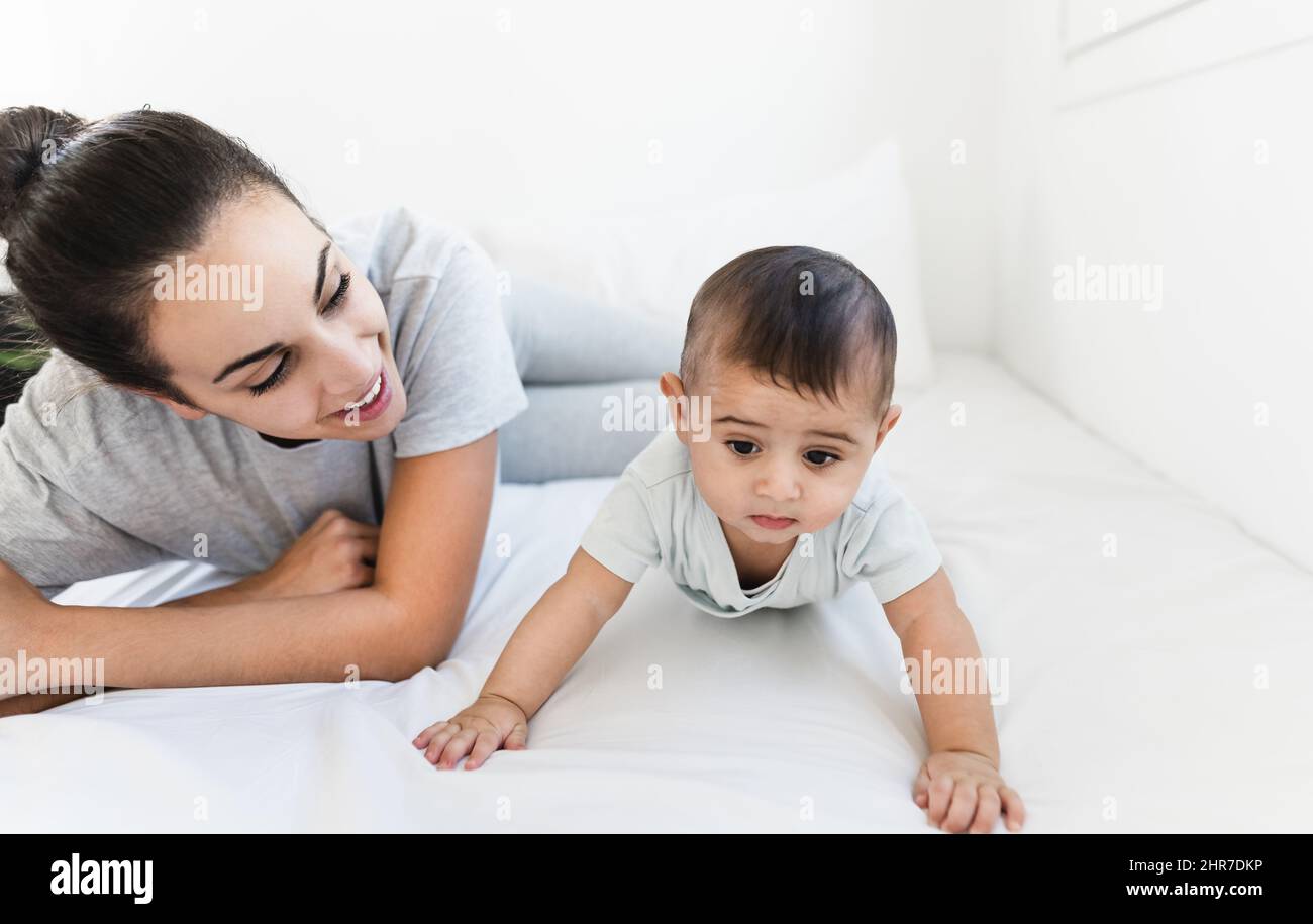 Glückliche Mutter, die mit ihrem kleinen Baby auf dem Bett liegt - Familien- und Mutterschaftskonzept Stockfoto