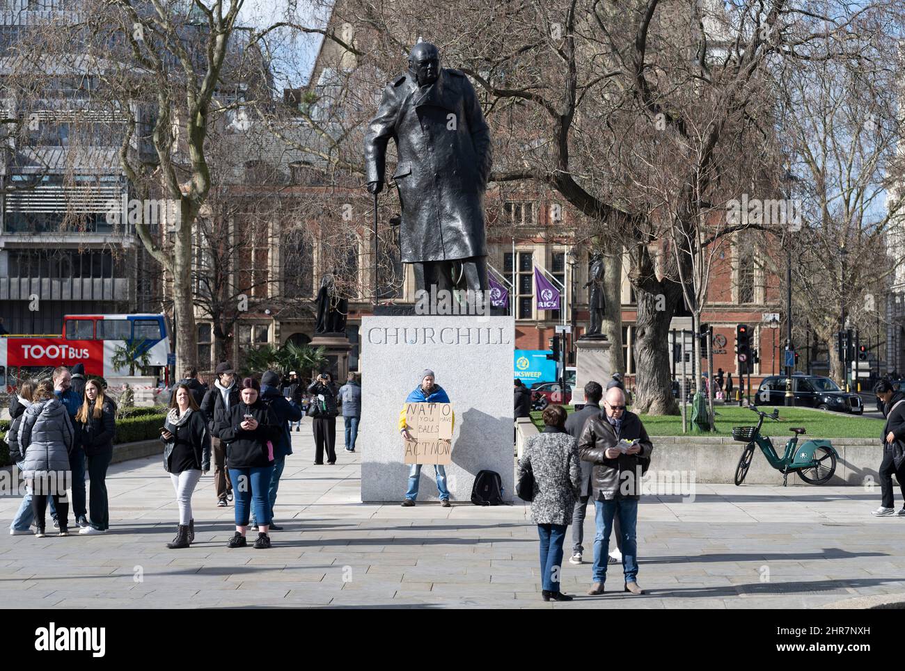 Parliament Square, London, Großbritannien. 25. Februar 2022. A , auf dem Parliament Square am 2. Tag der Invasion durch Russland, drapiert mit einer ukrainischen Flagge. Er hält ein Plakat, auf dem die NATO aufgefordert wird, jetzt zu handeln. Quelle: Malcolm Park/Alamy Live News Stockfoto