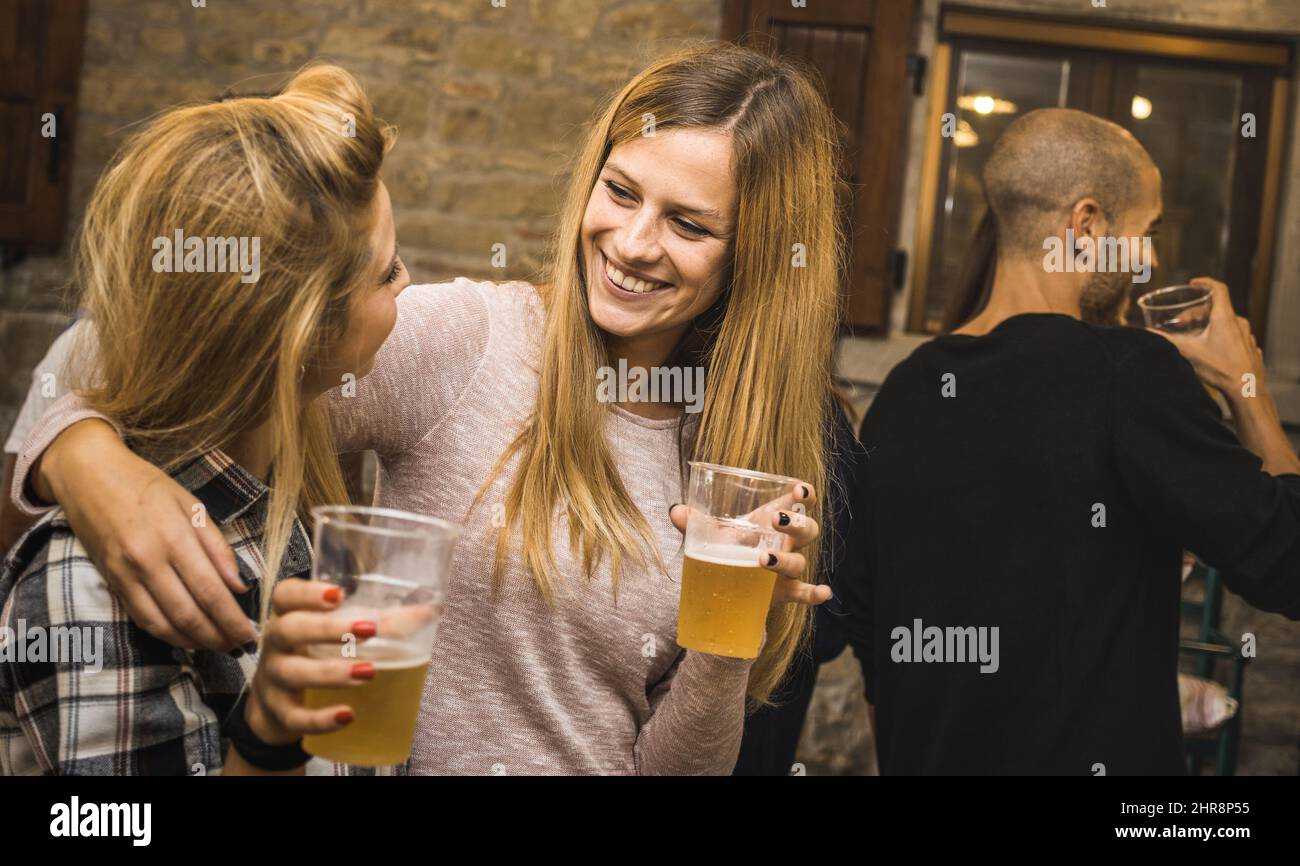 Glückliche Freunde trinken Bier auf der Hausfeier - Freundschaftskonzept mit ausgefallenen Menschen, die Spaß zusammen haben - Junge Frauen teilen Freude Moment feiern Stockfoto