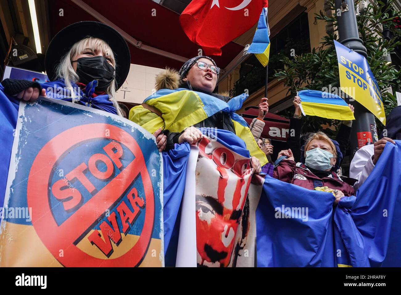 Ein Protestler hält ein Porträt von Wladimir Putin und eine riesige ukrainische Flagge, während er während der Demonstration Parolen singt.Ukrainische Bürger aus Istanbul versammelten sich vor dem russischen Generalkonsulat im Bezirk Beyo?lu und protestierten gegen die russische Militäroperation gegen die Ukraine. Die Protestierenden riefen unter dem Motto „Killer Putin“ und hielten Transparente mit „Nein zum Krieg“ und „Stoppt den Krieg“ auf und forderten, dass der Krieg gestoppt werden sollte So bald wie möglich während die Polizei umfassende Sicherheitsmaßnahmen ergriff, brachen einige Ukrainer in Tränen aus. Stockfoto