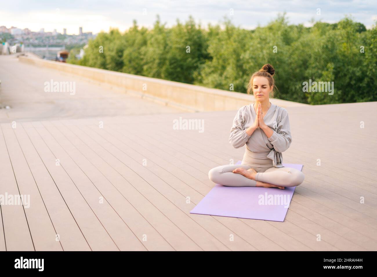 Porträt einer ruhigen kaukasischen jungen Frau, die Yoga praktiziert und Namaste-Posen mit geschlossenen Augen im Stadtpark ausführt. Stockfoto