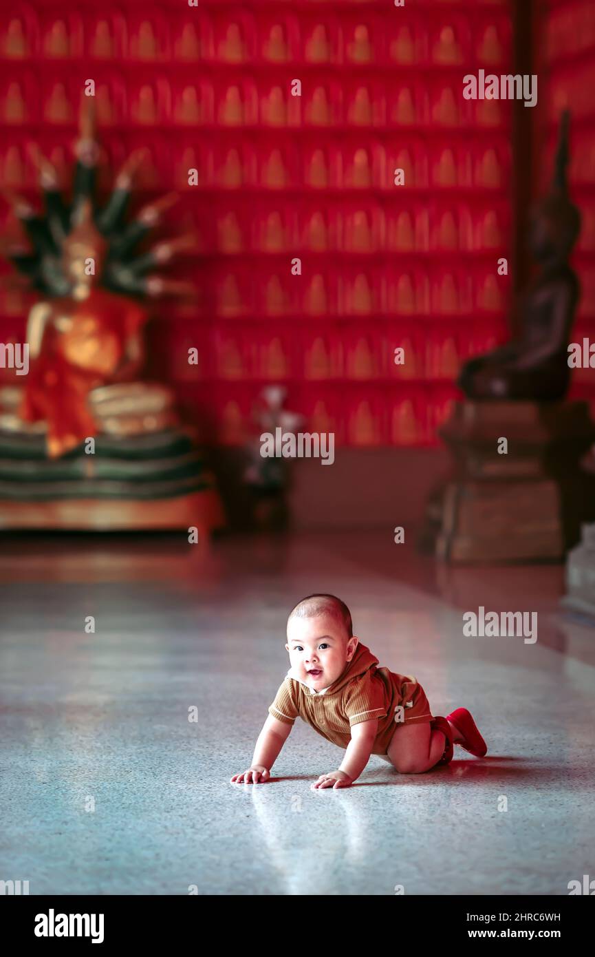 Kleiner Junge, der auf dem Boden eines thailändischen Tempels in Thailand kriecht Stockfoto