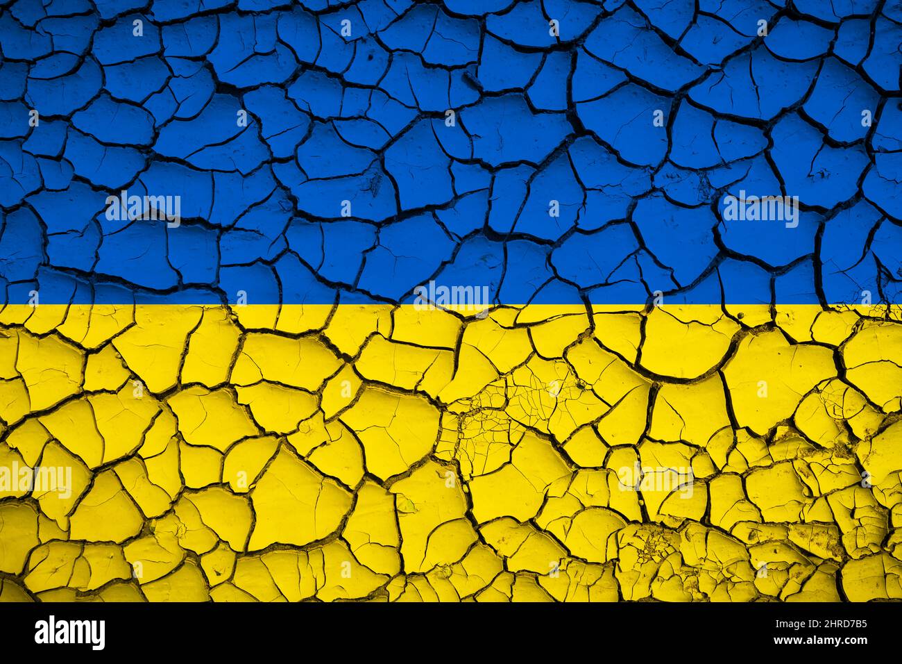 Ukrainische nationale blaue und gelbe Flagge auf einer Schlammstruktur von trockenen Rissen auf dem Boden Stockfoto