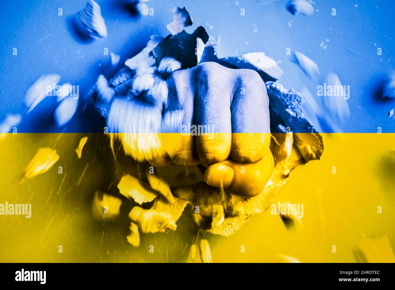 Eine Faust stanzt durch eine Betonwand mit den Farben der ukrainischen Nationalflagge. Das Konzept der russischen Aggression gegen die Ukraine Stockfoto