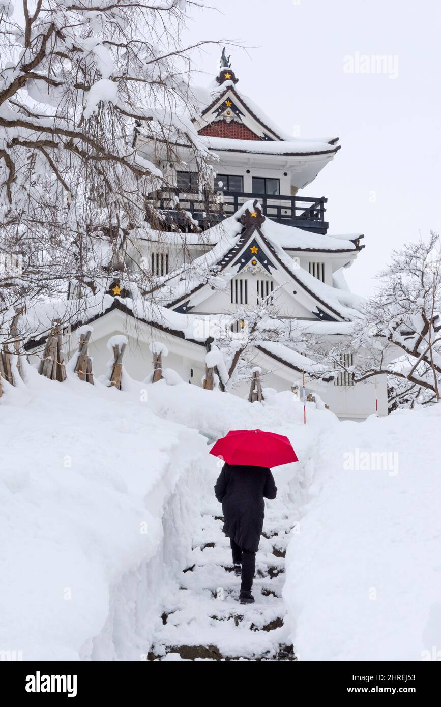 Tourist Walking on Snow with Red Schirm with Yokote Castle, Yokote, Präfektur Akita, Japan Stockfoto