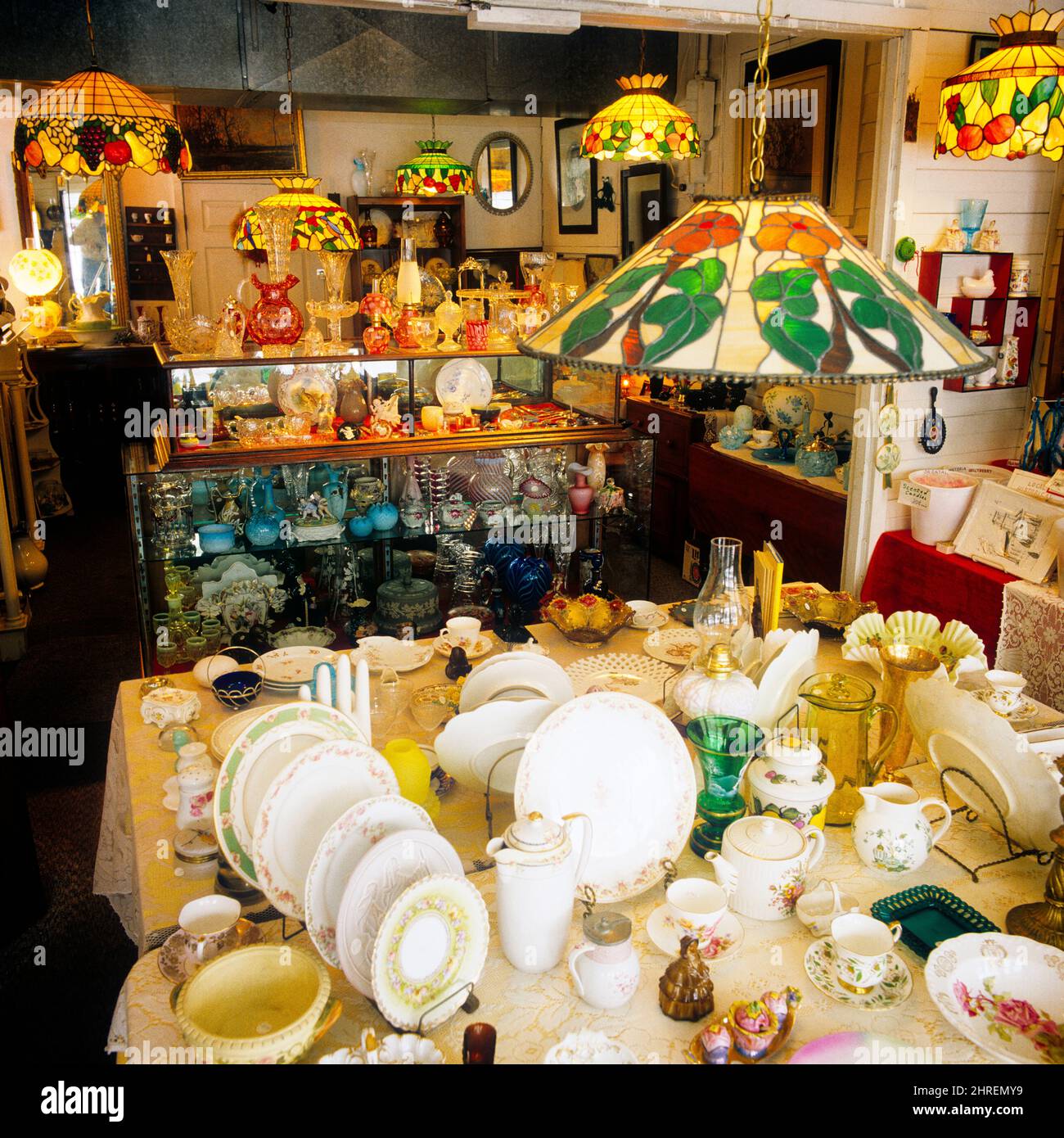 1980S INTERIEUR EINES ANTIQUITÄTENLADENS MIT LAMPENSCHIRMEN AUS BUNTGLAS UND EINER VIELZAHL VON GLAS UND CHINA COLLECTIBLES - KS19834 TEU001 HARS BLEIGLAS KONZEPTIONELL ENTERPRISE LAMPENSCHIRME STILVOLLE VIELFALT SECOND HAND COLLECTIBLES COMMERCE FLOHMARKT ENTSPANNUNG AMATEUR-UNTERNEHMEN FREUDE ALTMODISCH Stockfoto