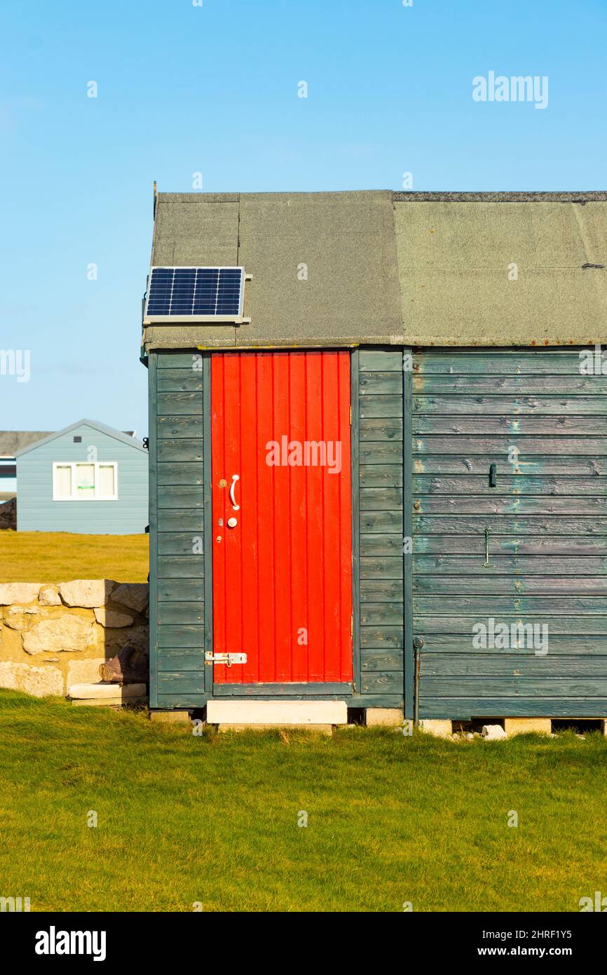 Lackierter dunkelgrüner Holzschuppen oder Chalet oder Strandhütte mit hellroter Tür auf der Isle of Portland, Portland Bill Stockfoto
