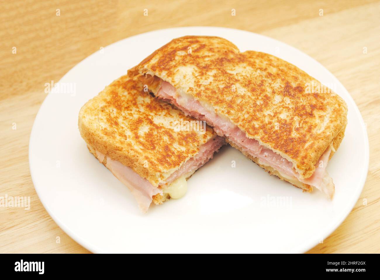 Gegrillter Käse und Schinken-Sandwich auf einem weißen Teller serviert Stockfoto
