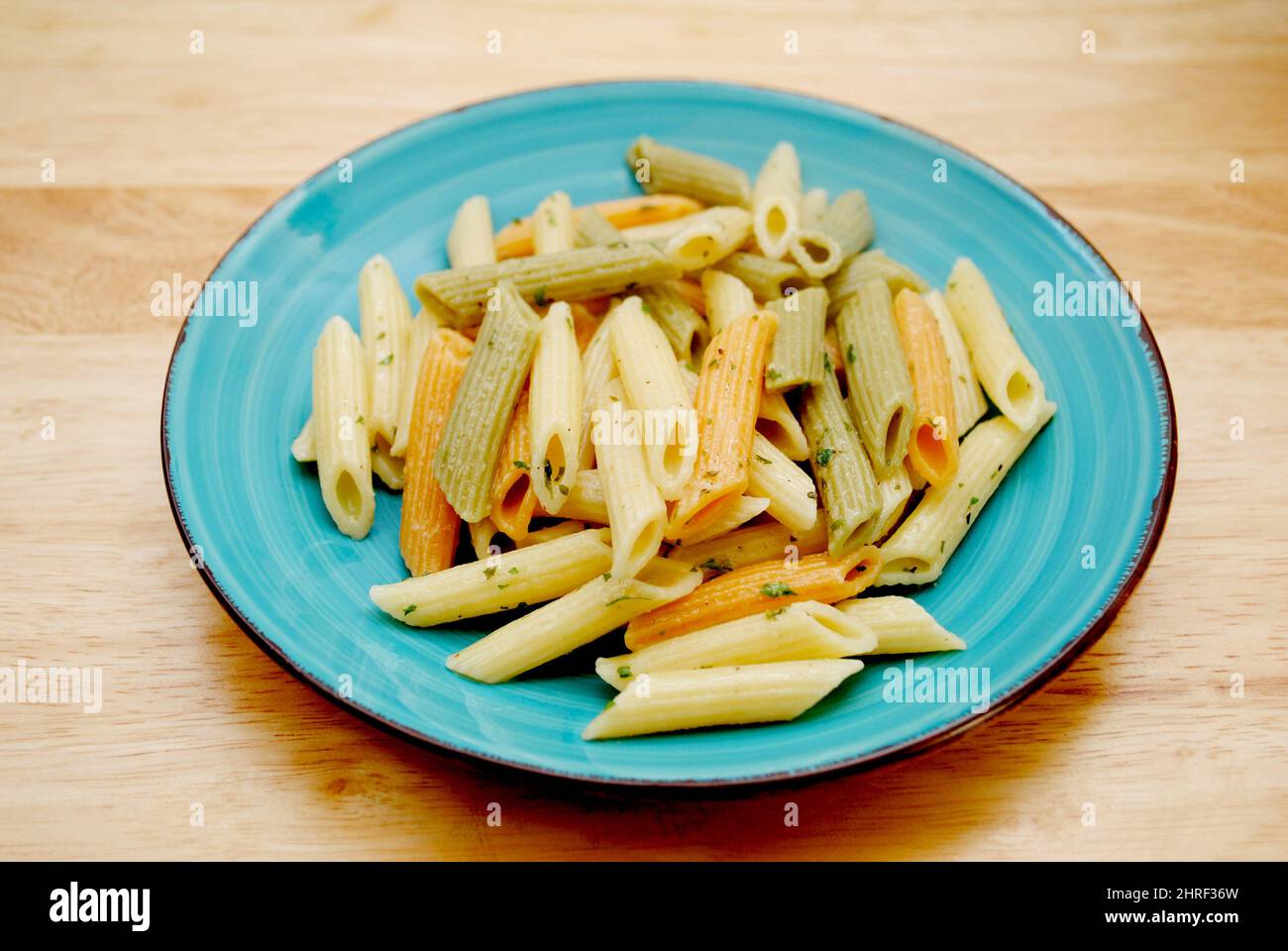 Teller gekochte zylinderförmige Penne Pasta Nudeln in drei Farben Gelb, Grün und Rot Stockfoto