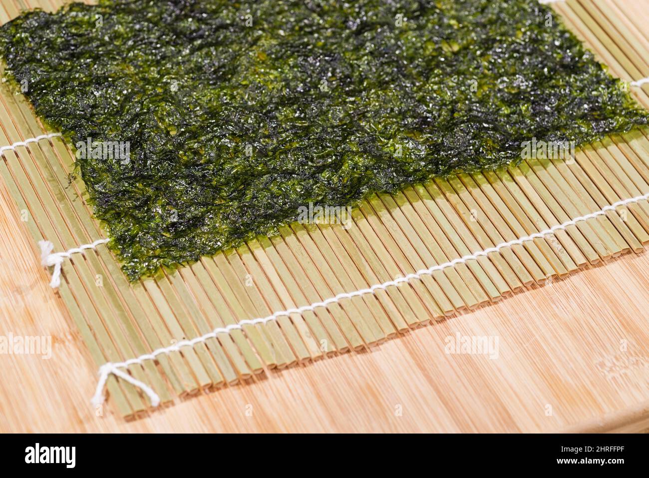 nori-Blatt und Bambusmatte auf einem Bambus-Schneidebrett für die Herstellung von Sushi-Rollen Stockfoto