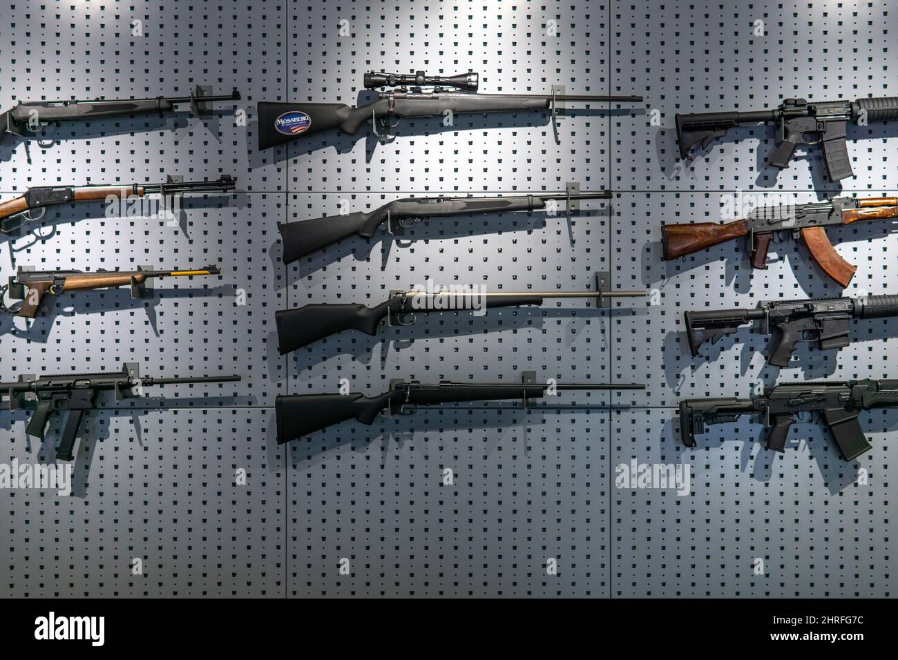 Sammlung von Gewehren und Karabinen. Verschiedene Schusswaffen hängen an speziellen Halterungen an der Wand. Waffenhintergrund. Stockfoto