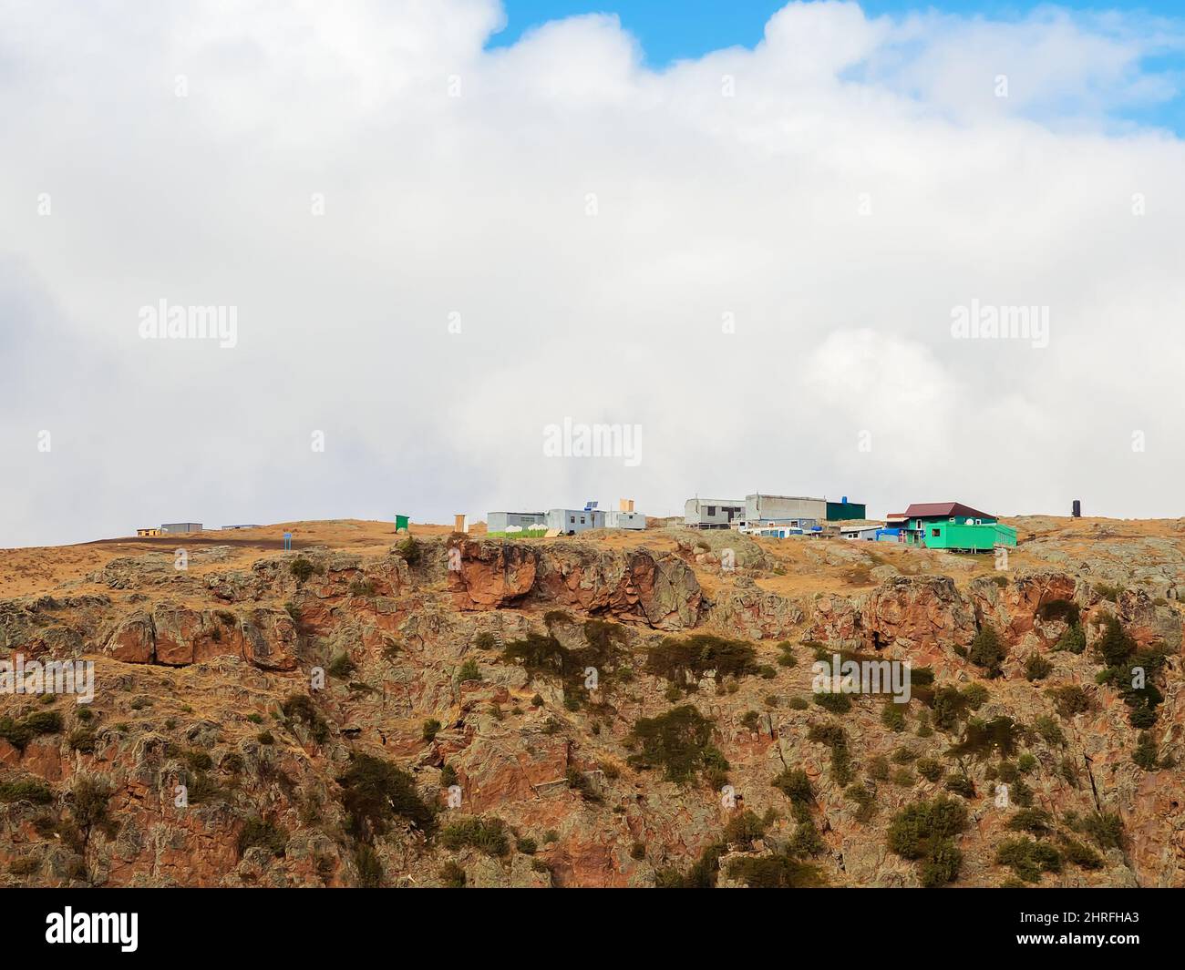 Ein Hochplateau im kaukasischen felsigen Hochland mit Lieferwagen und temporären Strukturen unter niedrig hängenden weißen Wolken Stockfoto