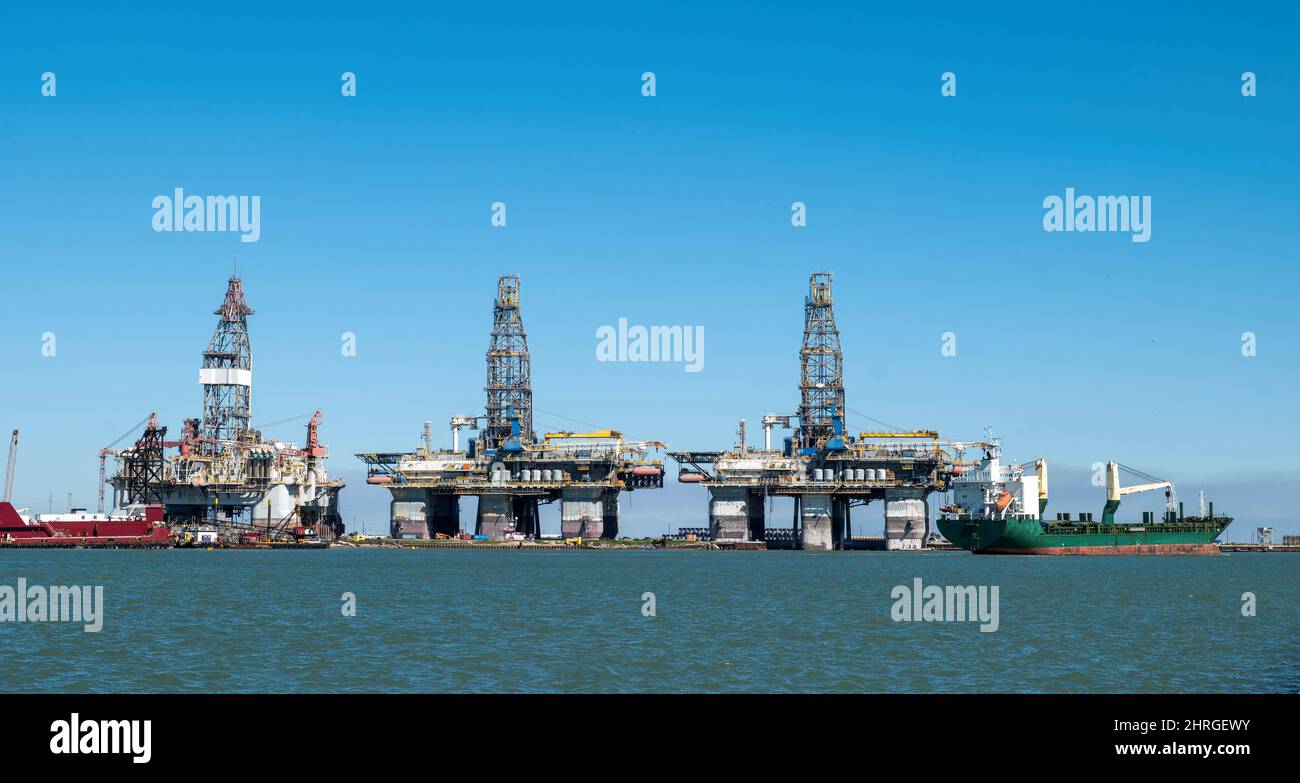 Ein Schiff segelt an drei Offshore-Bohrinseln im Trockendock entlang des Schifffahrtskanals in Port Aranas, Texas. Stockfoto
