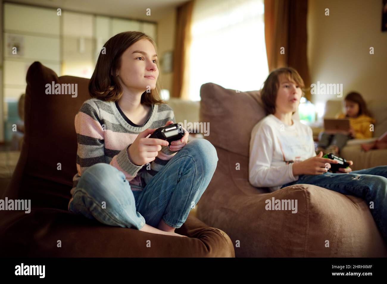 Eine Gruppe von Jugendlichen Kindern, die zu Hause Videospiele spielen. Kinder, die auf der Couch sitzen und Gaming-Controller halten. Familienspaß und Spaß im Innenbereich Stockfoto