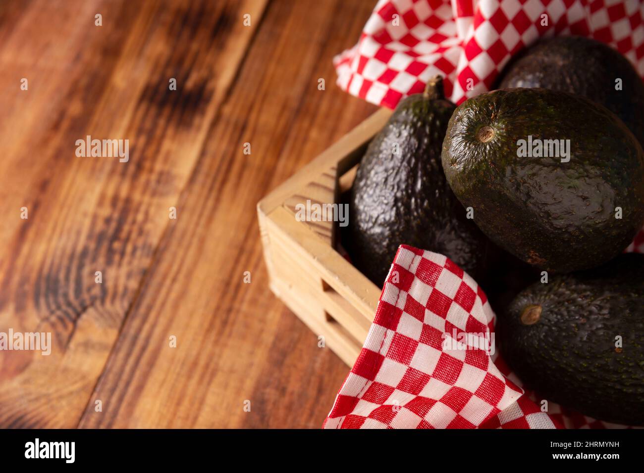 Mexikanische Avocado (Persea americana) auf rustikalem Holztisch. Hauptbestandteil zur Zubereitung von Guacamole. Nahaufnahme des Bildes mit Kopierbereich. Stockfoto