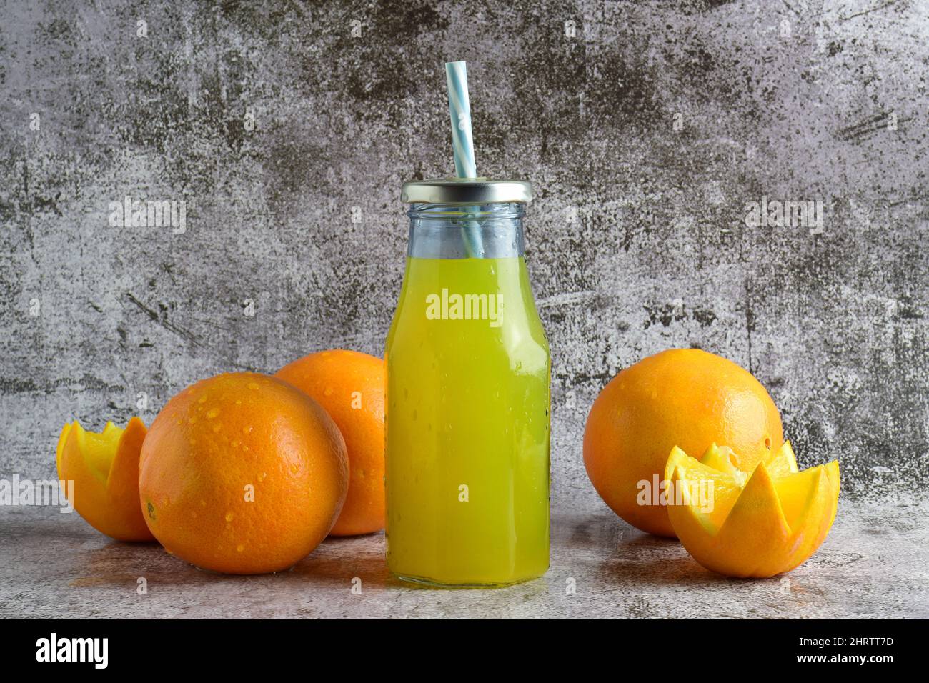 Glasflasche mit erfrischender Orangeade, Steinsockel in hellen Farben Stockfoto