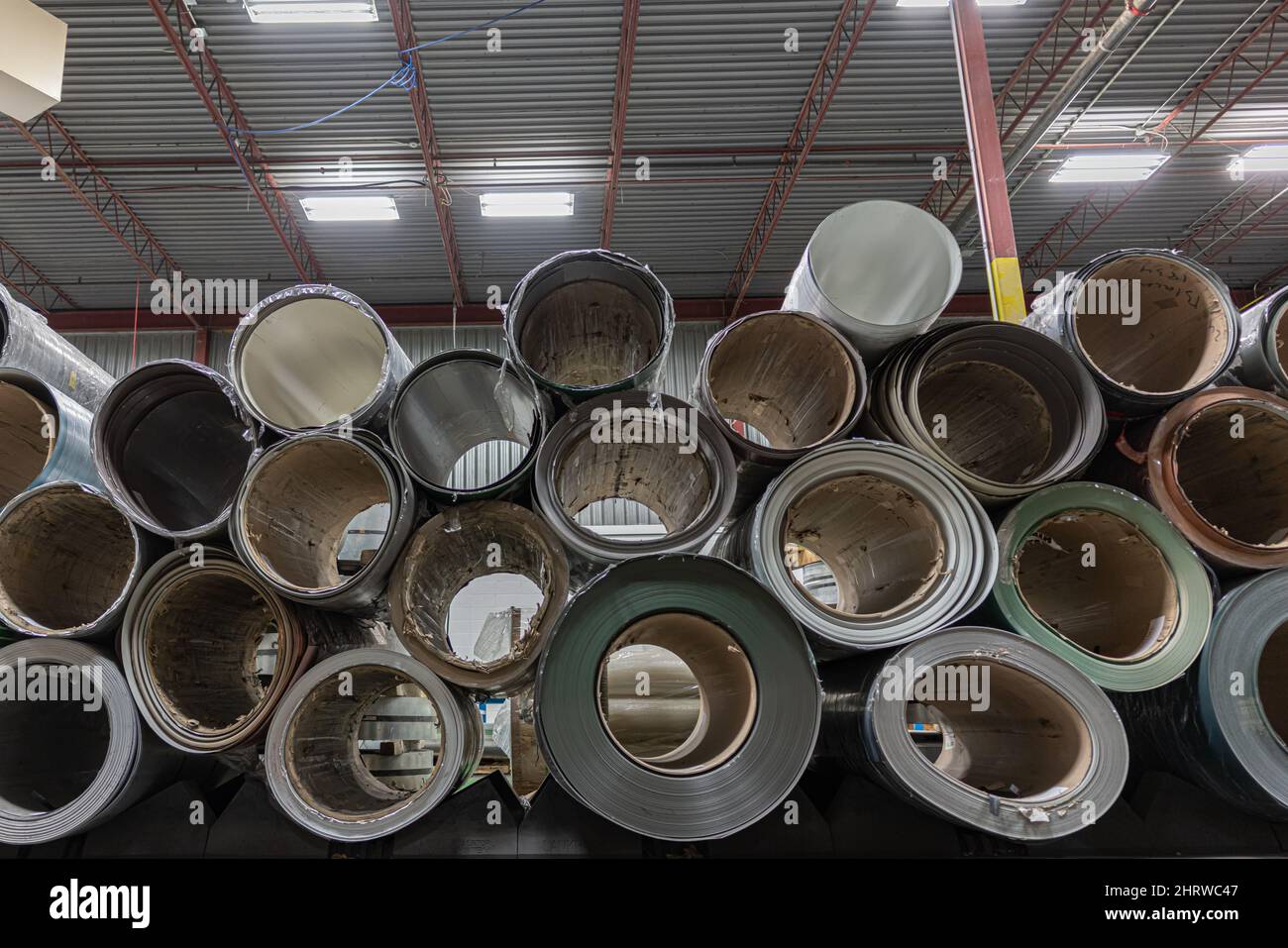 Stapel von Metallwalzen aus Spiralstahl in der Metalldachfabrik Stockfoto