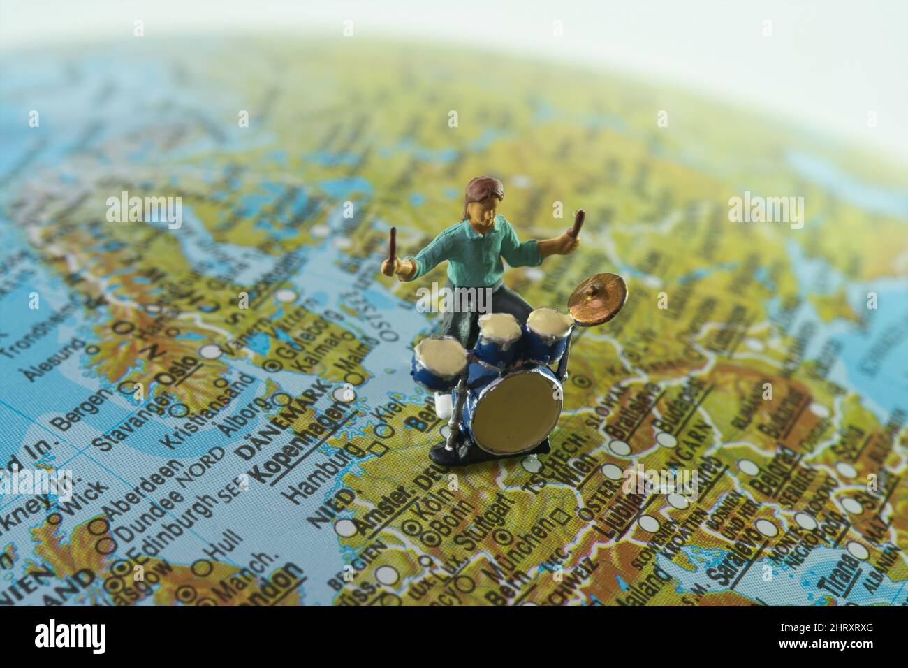 Ein Miniatur-Schlagzeuger spielt Musik auf einem Globus in der Region europa, in deutschland. Stockfoto