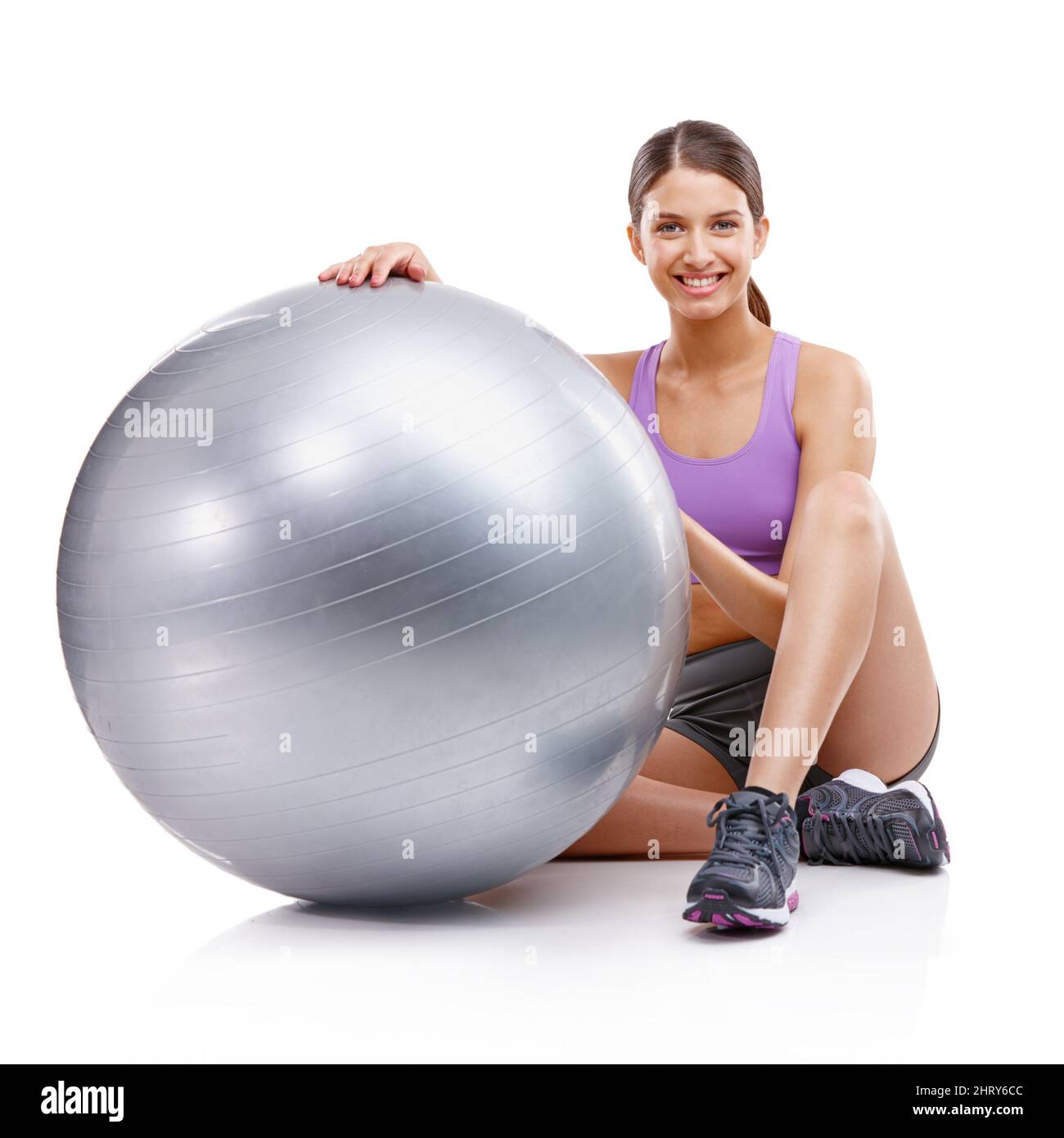 Jede Übung ist besser als keine Übung. Porträt einer jungen Frau, die neben ihrem Fitnessball sitzt. Stockfoto