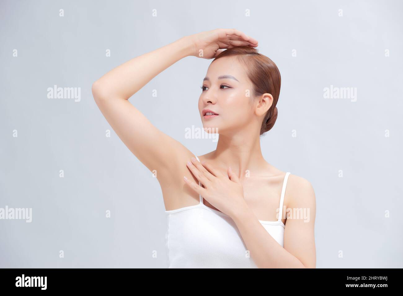 Schöne junge asiatische Frau, die die Hände hochhebt, um saubere und hygienische Achselhöhlen oder Achselhöhlen auf weißem Hintergrund zu zeigen Stockfoto