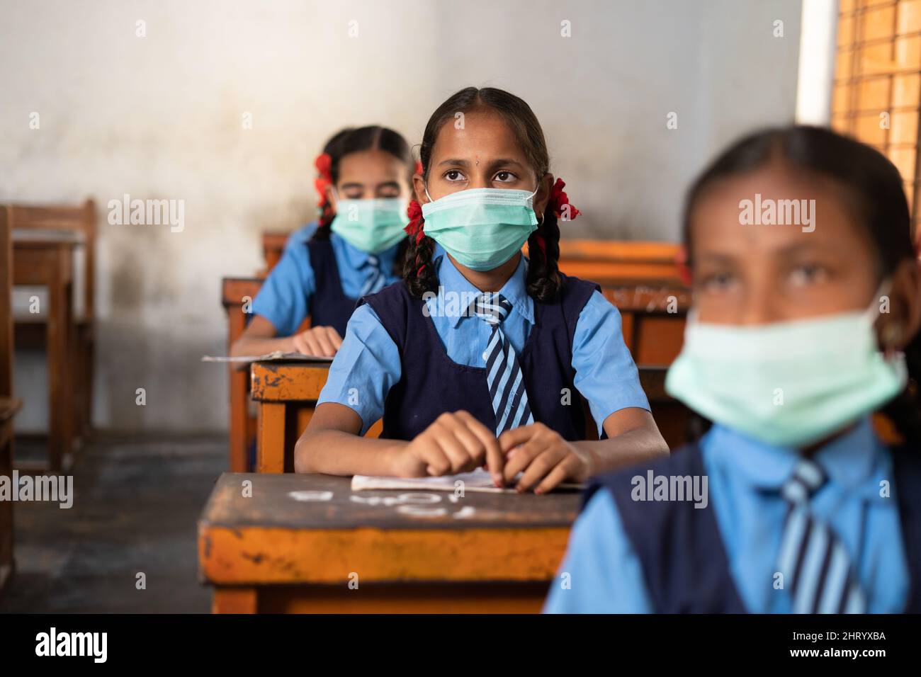 Mädchen Kind mit medizinischer Gesichtsmaske Hörklasse in der Schule unter Beibehaltung sozialer Distanz - Konzept des Coronavirus covid-19 Schutz, Verschmutzung Stockfoto