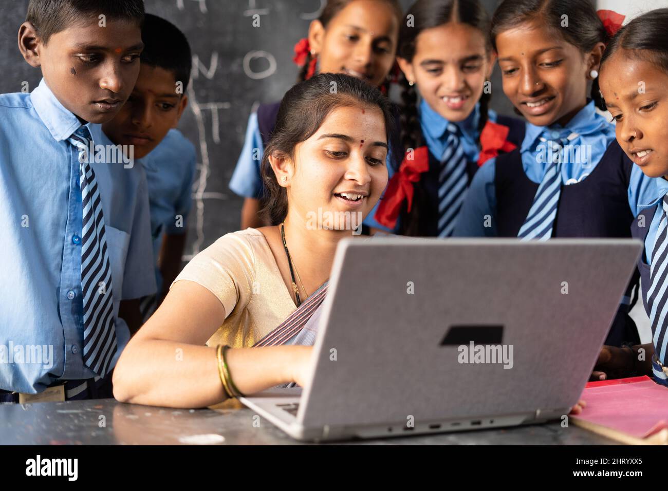 Junge indische Lehrerin, die mit Schuluniformstudenten im Klassenzimmer auf einem Laptop unterrichtet - Konzept der Entwicklung, Technologie und digitalen Bildung Stockfoto
