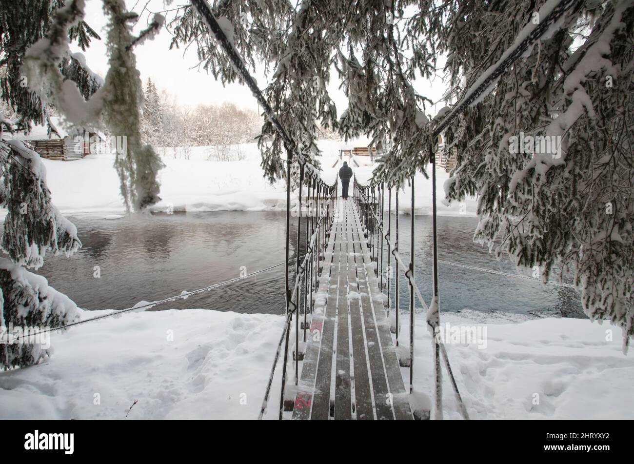Holzbrücke über einen Waldfluss. Frostfreie Gewässer. Einfrieren. Winterlandschaft im Wald Stockfoto